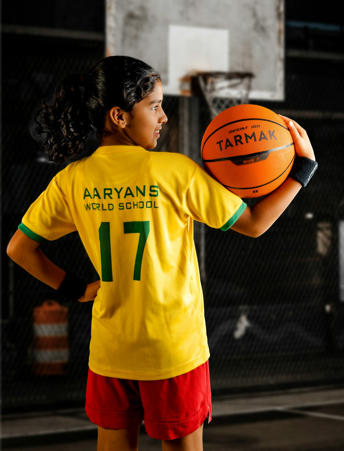 a young girl holding a basketball on a basketball court